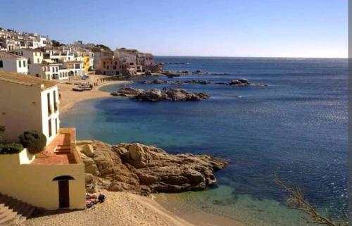a view of a beach with houses and the ocean at Apt con piscina en Calella de Palafrugell, parking gratuito in Calella de Palafrugell