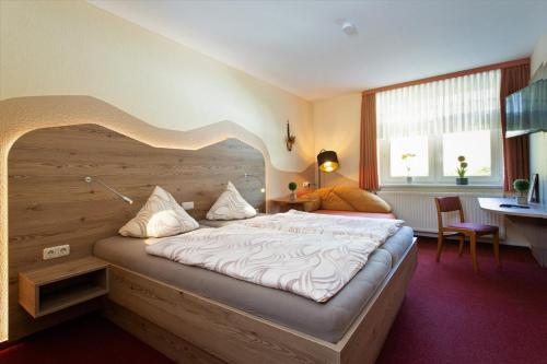 Schlafzimmer mit einem großen Bett mit einem Kopfteil aus Holz in der Unterkunft Landgasthof Zum Schützenhaus Sosa in Eibenstock