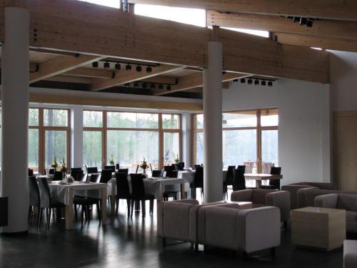 a dining room with tables and chairs and windows at Rezydencja nad jeziorem Pestkownica in Pestkownica