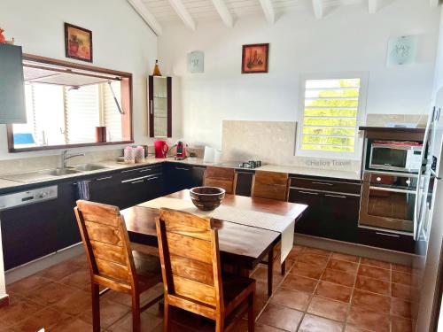 a kitchen with a wooden table and wooden chairs at Villa Le Refuge du Pirate in Deshaies