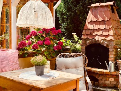 a patio table with a brick fireplace and flowers at Weißt Du noch - Gästehäuser & Suiten in Kühlungsborn