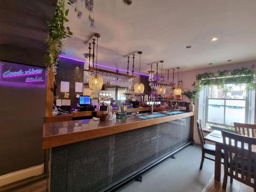 un bar en un restaurante con iluminación púrpura en The Dolphin Hotel en Pembroke Dock