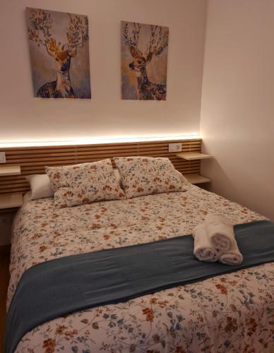a bed in a bedroom with two paintings on the wall at El Rinconcito de la Merced in Toledo