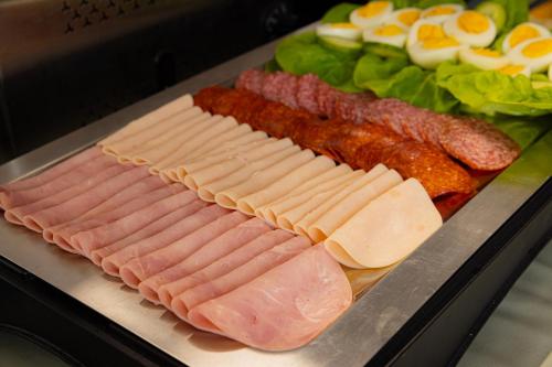 a tray with meats and eggs and a salad at Bazilika alatt Panzió in Esztergom