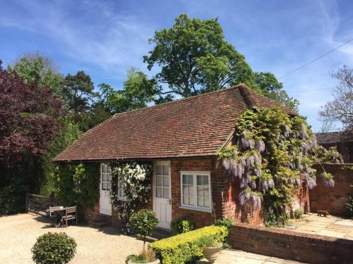 a small house is covered in purple flowers at Charming one bedroom cottage in Basingstoke