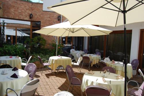 a patio with tables and chairs and an umbrella at Residence Hotel Balaton in Siófok