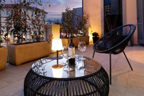 - une table avec des verres à vin et une lampe sur le balcon dans l'établissement La Terrazza 62, à Bergame