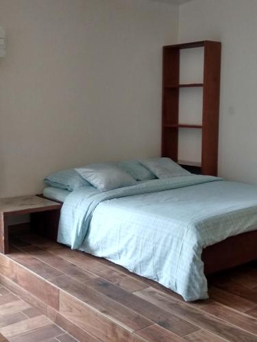 a bedroom with a bed and a wooden shelf at Studio cosy proche du volcan in Le Tampon