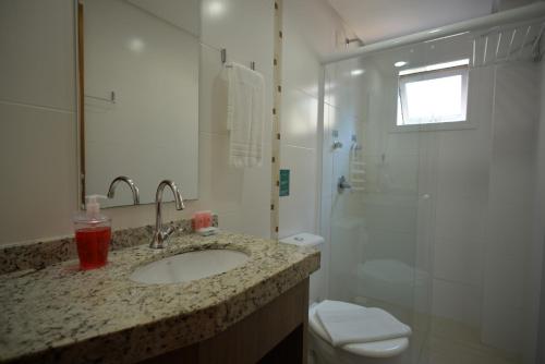 a bathroom with a sink and a shower and a toilet at Pousada Villa Maciel in Bombinhas