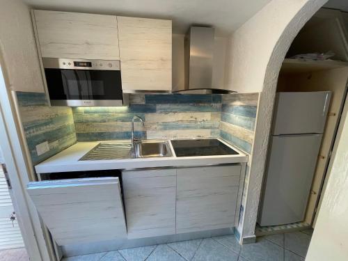 una piccola cucina con lavandino e frigorifero di Mono 4 posti vista mare "Il Portolano" a Porto Azzurro