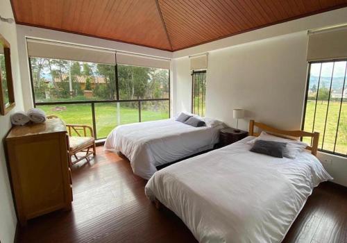 um quarto com duas camas e uma janela grande em Casa Campestre Villa Luna em Sogamoso