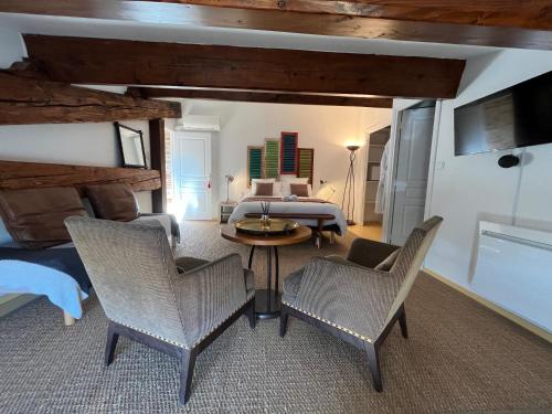 sala de estar con cama, mesa y sillas en Chai de Villeneuve, en Villeneuve-la-Rivière