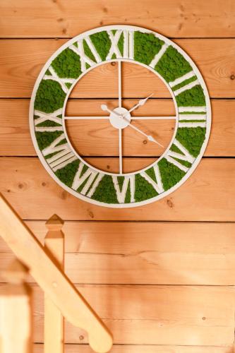 a clock is hanging on a wooden wall at Bajkowe Domki in Kudowa-Zdrój