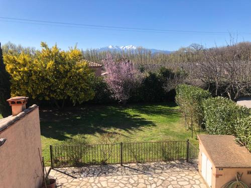 um jardim com cerca e alguns arbustos e árvores em AU MIMOSA -Gîte Le Canigou em Passa