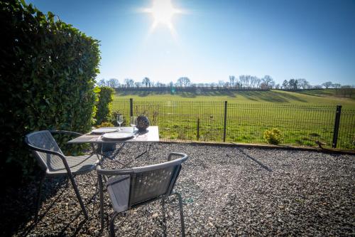 a table and chairs with a view of a field at La Chambre Du Pèlerin in Foy-Notre-Dame