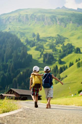 two people walking down a road with backpacks at Alpenlandhaus Alte Schule in Lermoos