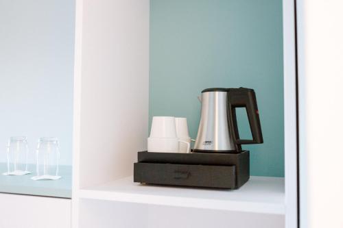 a coffee maker and glasses on a shelf at Hotel am Zoo in Neunkirchen
