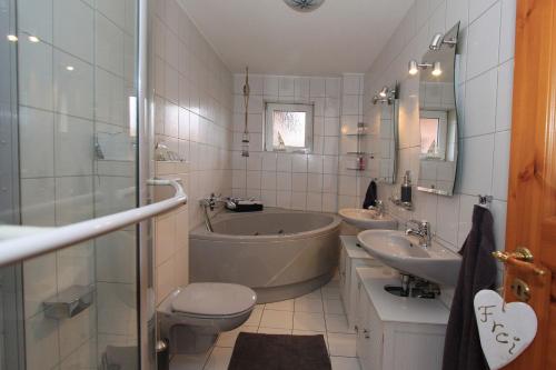 a bathroom with two sinks and a tub and a toilet at Ferienwohnung Strandgut in Behrensdorf