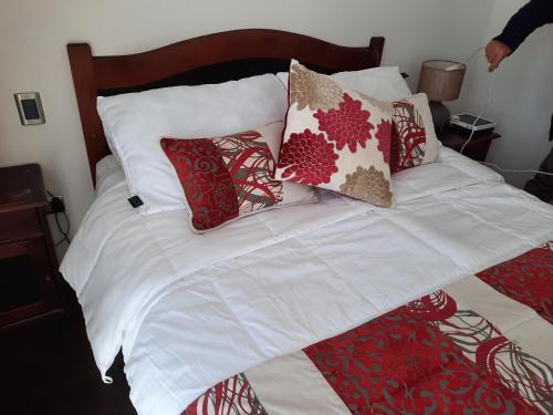 a bed with red and white pillows on it at Departamento en Condominio Mar Serena in La Serena