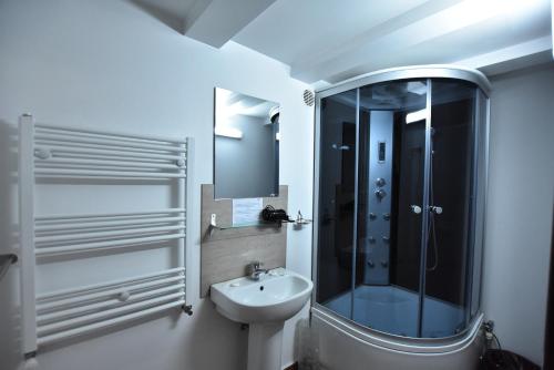 a bathroom with a sink and a shower with a mirror at Hotel Euphoria in Craiova