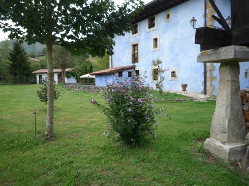 a blue building with a tree and flowers in a yard at Hotel Rural Sucuevas in Mestas de Con
