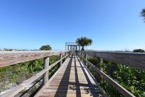 a wooden walkway over the beach with palm trees at Ocean Village Club R11 in Saint Augustine