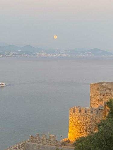 a full moon over the water and a castle at Harmony Butik Otel in Alanya