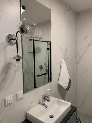 ein weißes Badezimmer mit einem Waschbecken und einem Spiegel in der Unterkunft Apartament Perłowy in Zamość