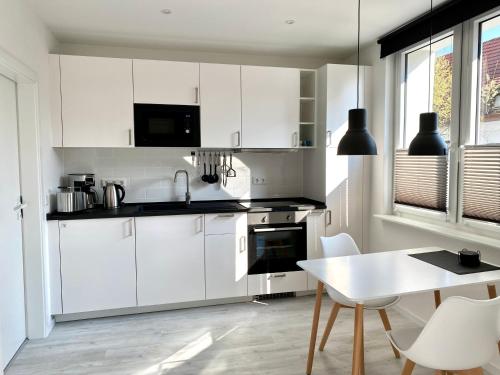 a kitchen with white cabinets and a table with chairs at Apartment Schloofschdubb in Fuldatal bei Kassel in Fuldatal