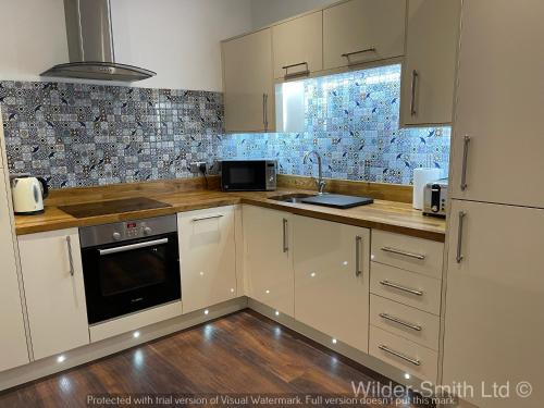 a kitchen with white cabinets and a stove top oven at Stylish 2-Bed Luxury Apartment in Nottingham City in Nottingham
