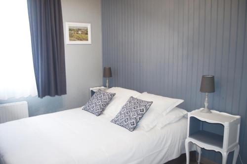 a bedroom with a white bed with pillows and a chair at Hotel Le Magnan in Avignon