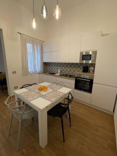 a kitchen with a white table and chairs and a kitchen with a stove at Casa Vacanze al Trenta3 in Marsala