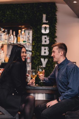 a man and woman sitting at a bar with glasses of wine at Business Hotel Plovdiv - Central Location in Plovdiv