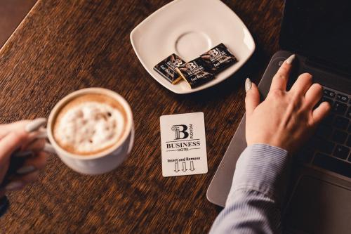 a person sitting at a table with a laptop and a cup of coffee at Business Hotel Plovdiv - Central Location in Plovdiv