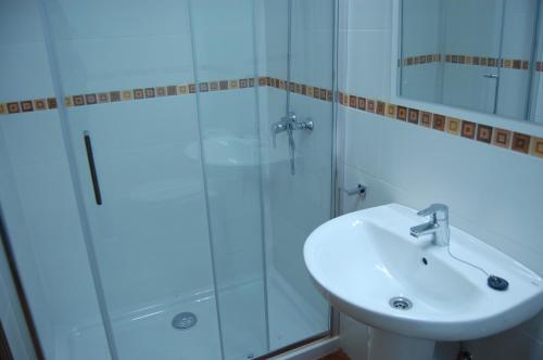 een badkamer met een wastafel en een glazen douche bij Vivienda Vacacional El Refugio in Llanes