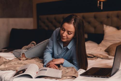 a woman laying on a bed reading a book at Business Hotel Plovdiv - Central Location in Plovdiv