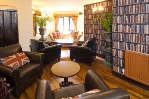 a living room with leather chairs and bookshelves at The Roundabout Hotel in Pulborough