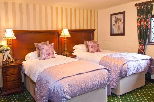 a hotel room with two beds and two lamps at The Roundabout Hotel in Pulborough