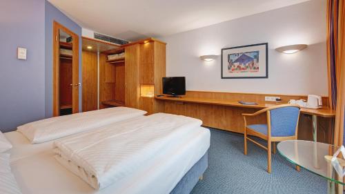 a hotel room with two beds and a desk at Hotel Schwanen Stuttgart Airport/Messe in Filderstadt