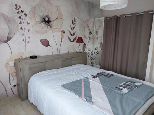 a bedroom with a bed with flowers on the wall at le pavillon in Bonnat