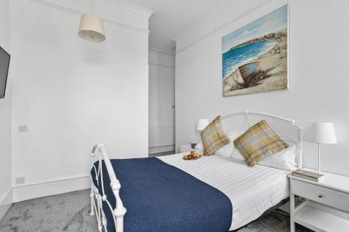 1 dormitorio con cama blanca y manta azul en The Belmont, en Torquay