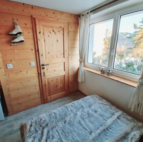 a bedroom with a bed and two windows in it at Heidi in Leysin