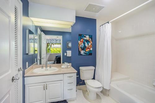 a blue bathroom with a toilet and a sink and a tub at Emmalani Court 312 condo in Princeville