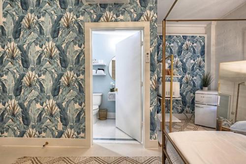 1 dormitorio con baño y papel pintado tropical en The Oleander Hotel Room 5 en Galveston