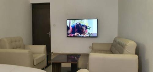 a living room with two chairs and a tv on the wall at Presken Hotel (Reliance) in Ikeja