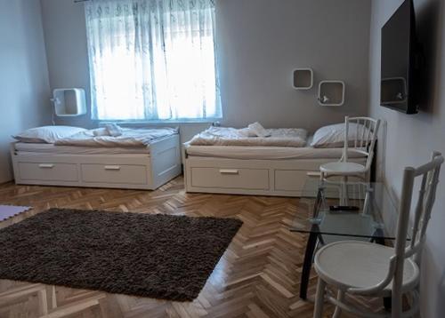 a room with two beds and a table and chairs at Hortenzia Vendégház Mór in Mór