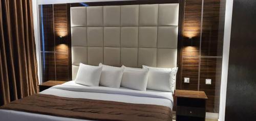 a bedroom with a large bed with a large headboard at Presken Hotel at International Airport Road in Ikeja