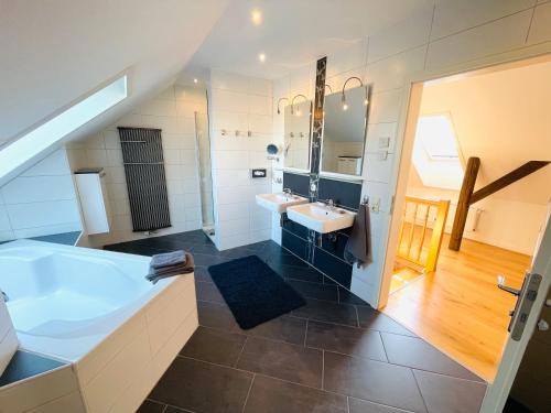 ein Badezimmer mit einer großen Badewanne und 2 Waschbecken in der Unterkunft Hof Steinhütten Boutique Apartments in Westerhever