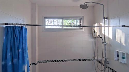 La salle de bains est pourvue d'une douche avec un rideau de douche bleu. dans l'établissement Happy house @ Casa Seaside Rayong, à Ban Chak Phai