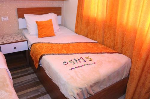 a small bedroom with a bed with an orange blanket at Osiris Hotel Cairo in Cairo